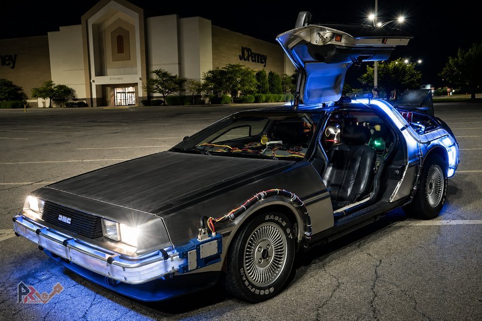 La DeLorean DMC-12 en tenue Retour vers le futur, de nuit, porte papillon ouverte